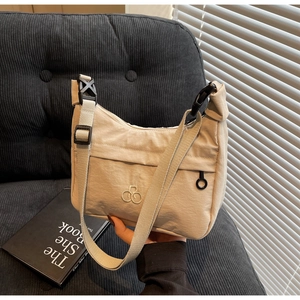 Dettaglio borsa beige in nylon con fibbia nera e logo ricamato su stile moderno
