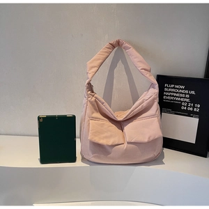 Close-up of pink puffer tote bag featuring double front flap pockets and wide shoulder strap