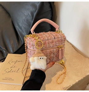 Detailed texture of pink tweed crossbody bag featuring chain strap and plush charm