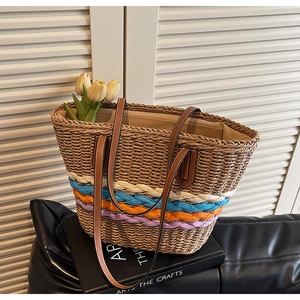 Close-up of woven straw tote bag featuring colorful braided bands and brown leather straps