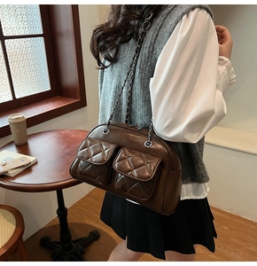 Detail of dark brown quilted crossbody bag with dual front pockets and metal chain straps