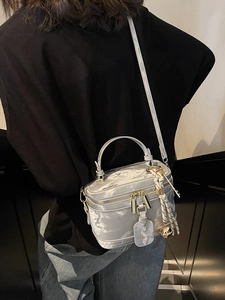 Sac boîte élégant en satin argenté avec poignée et bandoulière porté par un mannequin