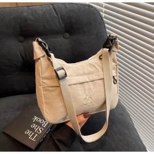 Dettaglio della borsa dumpling in nylon beige con tracolla regolabile e logo ricamato