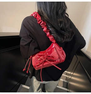 Detail of red patent leather shoulder bag with bow and ruffled strap on shoulder