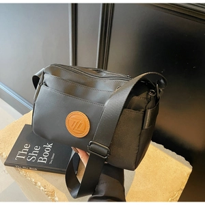 Gros plan du sac bandoulière noir à zips multiples avec sangle réglable et logo en cuir
