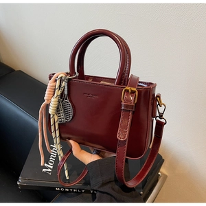 Close-up of a burgundy vintage handbag with glossy finish and tennis racket charm