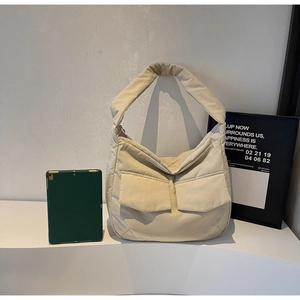 Detailed view of beige padded tote bag with large front pockets and quilted nylon texture