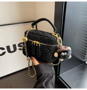 Detail of black tweed box bag with golden chain and funny plush monster charm