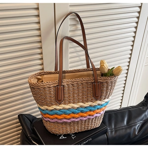 Detail of hand-woven straw tote with colorful stripes and brown leather handle
