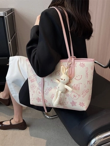 Off-white tote bag with pink straps, cartoon bear print and a plush bunny charm