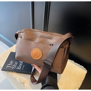 Sac bandoulière carré en nylon marron café avec plusieurs zips sur support en pierre