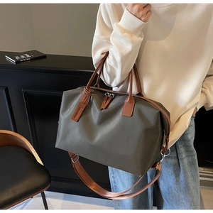 Detail of olive green nylon travel tote with leather straps and adjustable shoulder belt