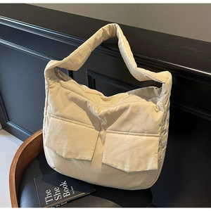 Close-up of quilted light beige tote bag with large front pockets and soft padded texture