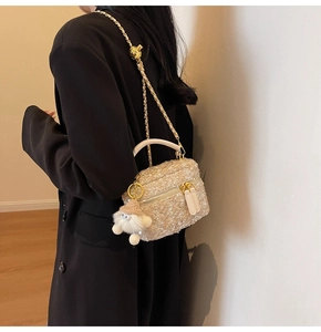 Detail of beige tweed crossbody bag with gold chain strap and fuzzy monster charm