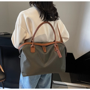 Detail of olive green nylon travel tote bag showing leather handles and zipper closure