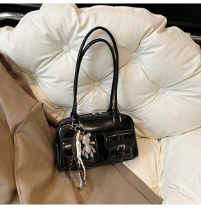Detail of glossy black patent leather Boston bag with double pockets and bear pendant