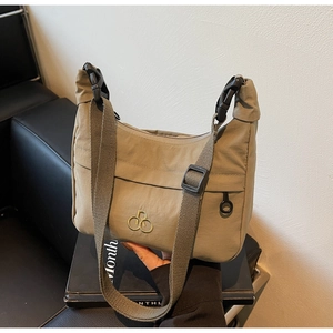 Dettaglio borsa a mezzaluna in nylon verde militare con tracolla regolabile e fibbia nera