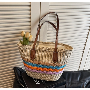 Detail of woven straw tote bag with colorful stripes and premium leather handle