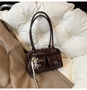 Detail of dark brown glossy patent leather shoulder bag with silver buckle pockets