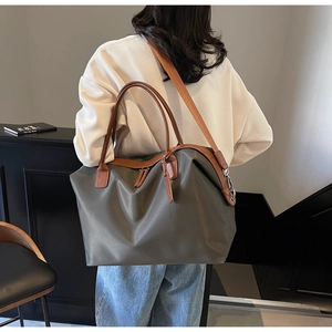 Detail of army green nylon tote bag featuring brown leather handles and wide shoulder strap