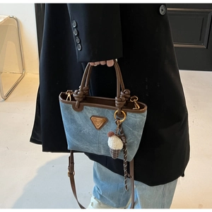 Detail of blue denim tote bag with leather handles and plush ice cream charm