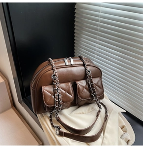 Detail of vintage brown quilted crossbody bag featuring dual front pockets and silver zippers