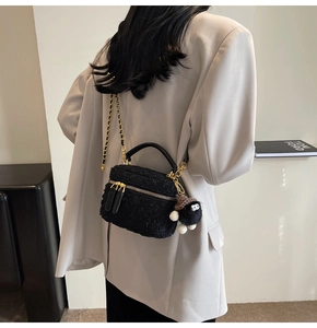 Detailed shot of black tweed crossbody bag with gold chain and plush charm