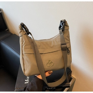 Dettaglio della borsa in nylon verde oliva con logo dorato e tracolla regolabile