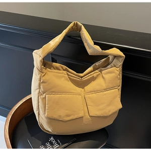 Detail of yellow quilted puffer tote bag with oversized front flap pockets on a chair