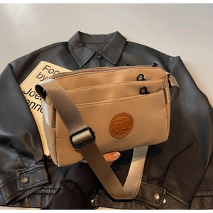 Gros plan du sac bandoulière kaki avec plusieurs poches zippées et bandoulière large