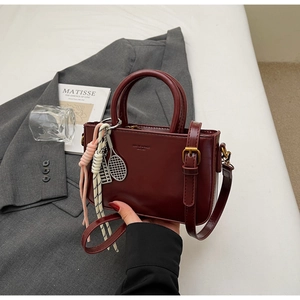 Detail view of burgundy vintage small square bag featuring metal charms and logo