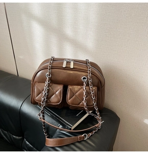 Close-up of brown quilted pockets and silver chain detail on a retro pillow bag