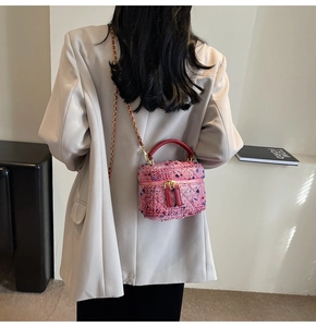 Detail of pink tweed quilted box bag with red leather handle and gold chain strap
