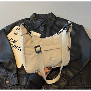Dettaglio della borsa a tracolla in nylon beige con logo ricamato e tracolla regolabile