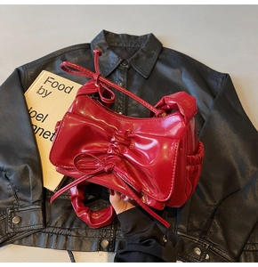 Detailed view of a bright red pleated bow handbag on a premium black leather background