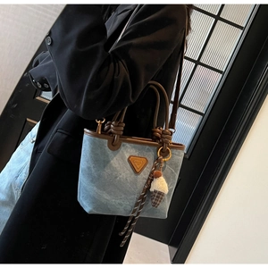 Detail of blue denim tote bag with brown leather knotted handles and ice cream charm