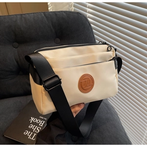 Détail du sac à bandoulière en nylon beige avec plusieurs poches zippées superposées