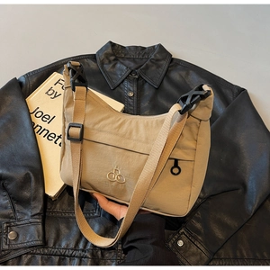 Dettaglio borsa beige con stemma dorato e fibbia nera su giacca di pelle