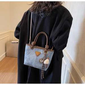 Blue denim bucket bag with brown leather handles and ice cream charm worn by a model