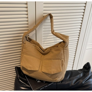 Detailed side view of khaki canvas tote bag featuring large utility front pockets and zip closure