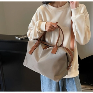 Detail of grey nylon tote bag with brown leather handles and side brand tag on model