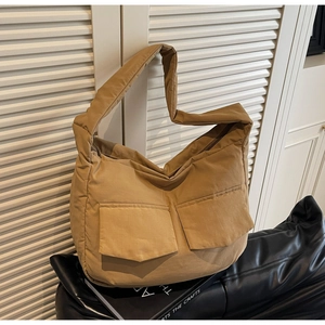 Detail view of khaki padded tote bag featuring two front pockets and wide shoulder strap