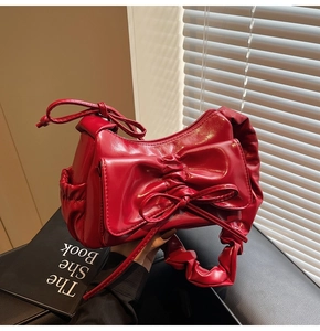 Detailed view of red glossy PU leather shoulder bag with bow and ruched handle