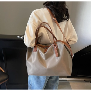 Detail of khaki nylon tote bag showing adjustable shoulder strap and premium PU handle