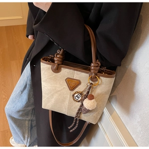 Detail of canvas bucket bag with leather trim, stylish charms and adjustable shoulder strap
