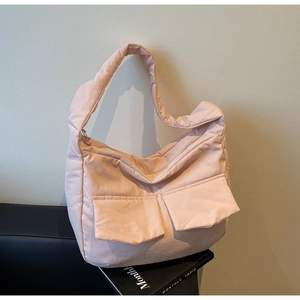 Detail of light pink quilted tote bag showing soft padded fabric and dual front pockets