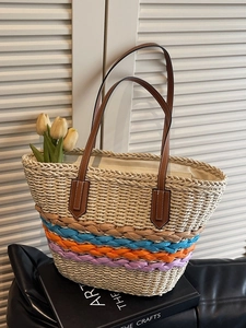 Woven straw beach tote bag with colorful striped base and brown leather handles
