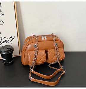 Detail of caramel quilted faux leather handbag with silver chain strap and twin front pockets