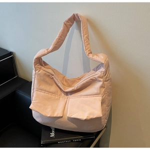 Detailed close-up of light pink quilted tote bag with large front pockets and matte texture