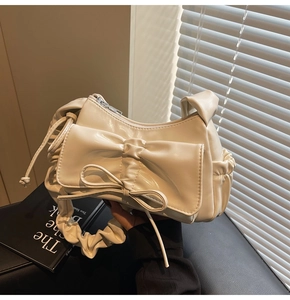 Detailed view of the pleated handle and bow knot design on the cream PU leather handbag